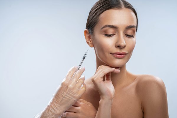 Prick of beauty. Beautiful girl standing isolated on white and preparing for beauty procedure