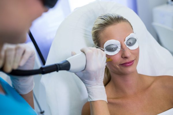 Woman receiving laser epilation treatment on her face at beauty salon