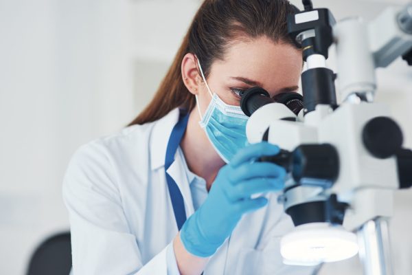 Microscope, scientist and investigation in research laboratory for medicine, biology and pharmaceuticals. Female person, healthcare and technician in pathology, test or science for vaccine innovation.