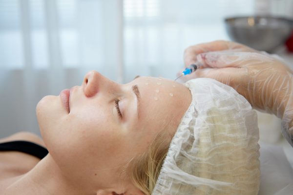 Beautician makes mesotherapy injections. spa beauty treatment, skincare. Woman getting facial care by beautician at spa salon, side view. Wellness center. Healthcare occupation